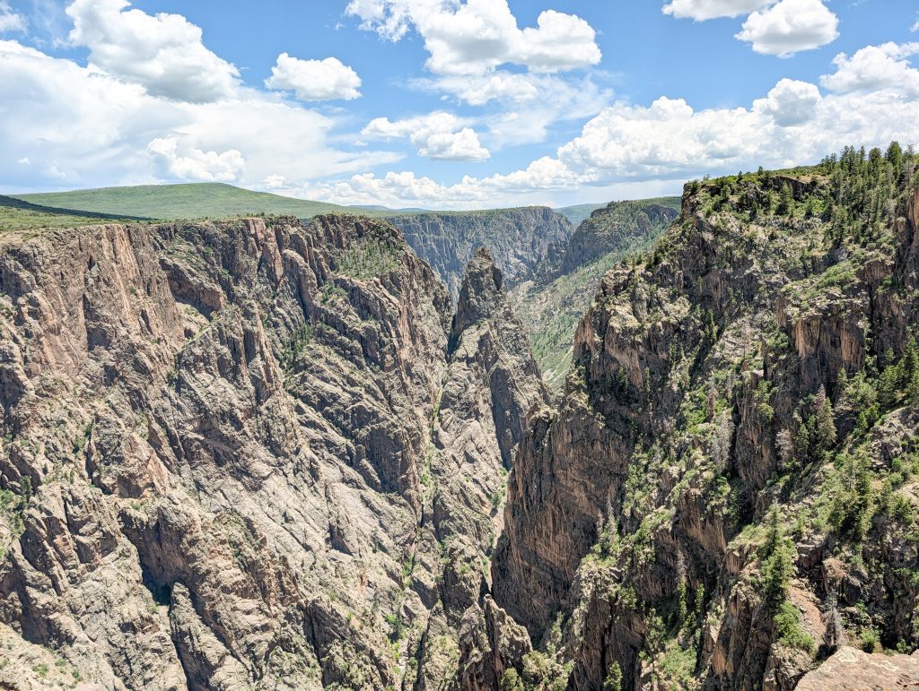 Deep, jagged vertical rock columns and crags seen from the Cross Fissures View overlook in Black Canyon of the Gunnison, CO.