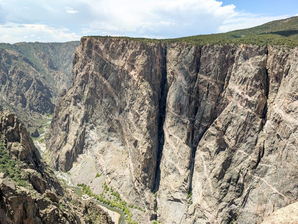 The Painted Wall cliff at Black Canyon of the Gunnison National Park, featuring distinct pink pegmatite veins across the dark rock.